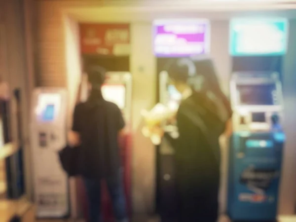 Imagen borrosa de las personas se alinean para utilizar la máquina de la banca o cajero automático (cajero automático) para depositar en la ciudad por la noche y puede ser una ilustración para el artículo de uso de personas cajero automático —  Fotos de Stock