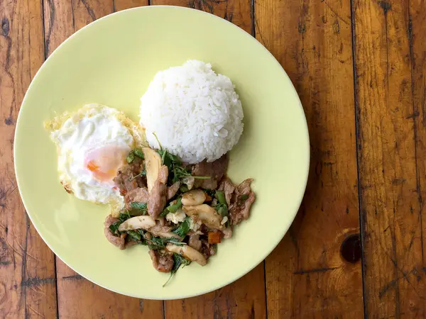 Thai pedas makanan kemangi babi goreng resep nasi (Krapao Gai) dengan telur goreng di piring hijau di kayu latar. Thai Food . — Stok Foto