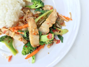 Kavrulmuş Chili Yapıştır ve karışık sebze soslu kızarmış gevrek domuz eti ilave edin; fesleğen; Kale; brokoli; havuç; kırmızı biber ve sahanda yumurta beyaz arka plan üzerinde beyaz tabak içinde Tayland Yasemin pirinç ile. Tay tarzında gıda.