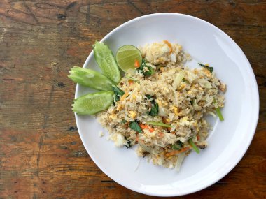 Uskumru ile Asya kızarmış pilav; yumurta ve beyaz tabak sebze ahşap arka plan üzerinde slayt salatalık ile hizmet vermektedir. Tay tarzında gıda.