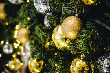 Dalların üzerindeki altın ve gümüş rengi Noel balosu. Süslü Noel ağacı ile süslenmiş köknar ağacı. Yeni Yıl Dekorasyon Şenliği arka planında klasik bir ton ve seçici bir odak var. Boşluğu kopyala.