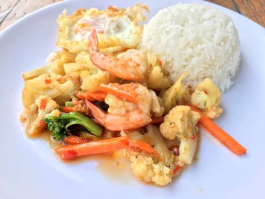 fasulye ve pilav ve kızarmış yumurta ahşap arka plan üzerinde beyaz tabak karides sebzeler ile tavada. Tay tarzında gıda.