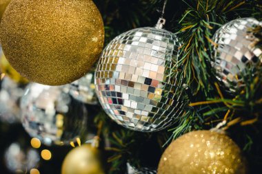 Dalların üzerindeki altın ve gümüş rengi Noel balosu. Süslü Noel ağacı ile süslenmiş köknar ağacı. Yeni Yıl Dekorasyon Şenliği arka planında klasik bir ton ve seçici bir odak var. Boşluğu kopyala.