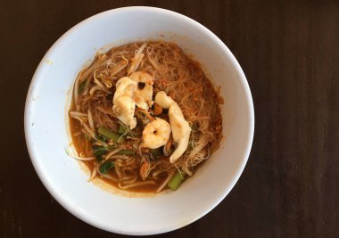 Tay şehriye Tom Yum, baharatlı deniz ürünleri çorbası rustik ahşap masa üzerinde bir kase erişte, geleneksel Tay gıda tarzı