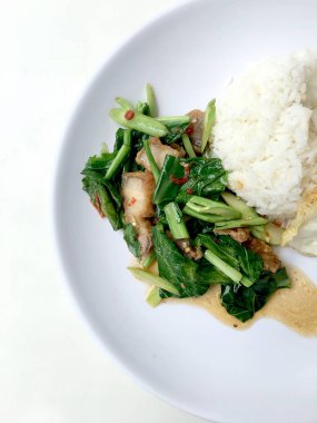 Fry stir Kai arazi ve gevrek domuz eti, beyaz arka plan üzerinde beyaz tabak kızarmış pilav pilav ile karıştırın. Tay tarzında gıda.