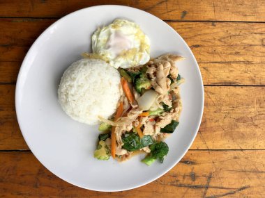 karışık sebze ve pirinç eski ahşap masa üzerinde beyaz tabak içinde Tay tarzında kızarmış yumurta ile tavada kızartılmış tavuk. Asya Tayland gıda.