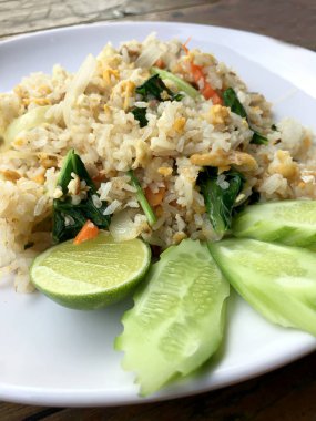 Uskumru ile Asya kızarmış pilav; yumurta ve beyaz tabak sebze ahşap arka plan üzerinde slayt salatalık ile hizmet vermektedir. Tay tarzında gıda.