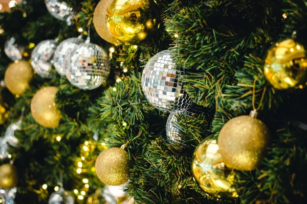 Dalların üzerindeki altın ve gümüş rengi Noel balosu. Süslü Noel ağacı ile süslenmiş köknar ağacı. Yeni Yıl Dekorasyon Şenliği arka planında klasik bir ton ve seçici bir odak var. Boşluğu kopyala.