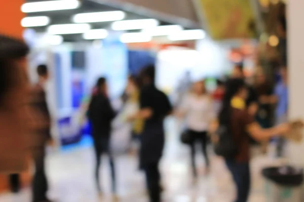 Abstract blurred image of people walking in shopping centre or exhibition hall event background.