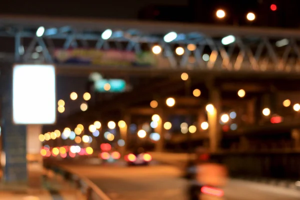 blurred image of billboard blank for outdoor advertising poster,  blank billboard in night time for advertisement on road with abstract circular bokeh motion lens blur of city and street light.
