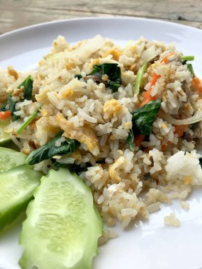 Uskumru ile Asya kızarmış pilav; yumurta ve beyaz tabak sebze ahşap arka plan üzerinde slayt salatalık ile hizmet vermektedir. Tay tarzında gıda.