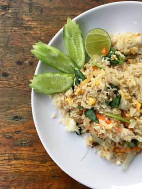 Uskumru ile Asya kızarmış pilav; yumurta ve beyaz tabak sebze ahşap arka plan üzerinde slayt salatalık ile hizmet vermektedir. Tay tarzında gıda.