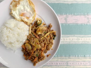 domates biber sosu ve pilav ve kızarmış yumurta ve domates biber daldırma ile beyaz tabak sebze ile kıyılmış domuz kızarmış. Tay tarzında gıda.