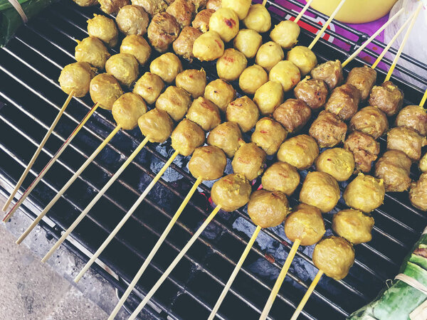 Тайские фрикадельки на гриле на стальной плите в огне на рынке. Тайская уличная еда. винтажный тон
.