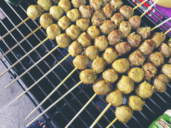 Тайские фрикадельки на гриле на стальной плите в огне на рынке. Тайская уличная еда. винтажный тон
.