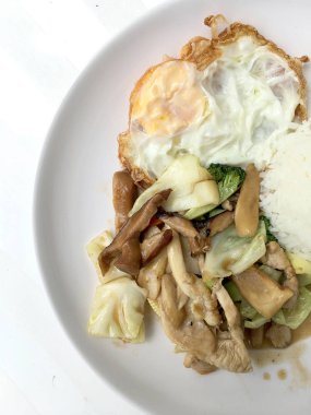 Tavada kızartılmış mix sebze, mantar ve bitki buhar pirinç ve beyaz arka plan üzerinde beyaz plaka tarzında Tayland kızarmış yumurta ile. Tay lokanta sıralama yapmak.