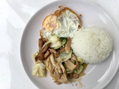 Tavada kızartılmış mix sebze, mantar ve bitki buhar pirinç ve beyaz arka plan üzerinde beyaz plaka tarzında Tayland kızarmış yumurta ile. Tay lokanta sıralama yapmak.