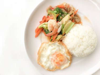 Kızarmış lezzetli shimp ve kızarmış yumurta beyaz arka plan üzerinde beyaz tabak pirinç Tay ev yapımı yemek ya da restoranda yemek tarifi olarak hizmet ile karışık sebze sote. Tay tarzında gıda.