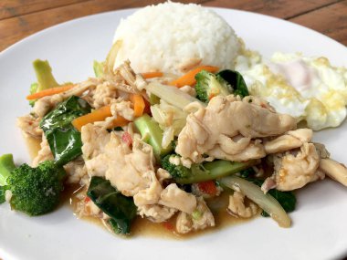 karışık sebze ve pirinç eski ahşap masa üzerinde beyaz tabak içinde Tay tarzında kızarmış yumurta ile tavada kızartılmış tavuk. Asya Tayland gıda.