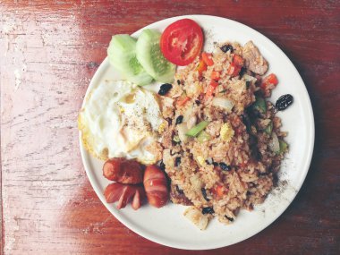 Amerikan tarzı kahvaltı seti, pirinç ve stil kızarmış yumurta ve sosis ahşap masa üzerinde beyaz tabak kızarmış. Tay yemeği. Vintage rengi.