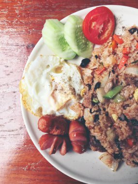 Amerikan tarzı kahvaltı seti, pirinç ve stil kızarmış yumurta ve sosis ahşap masa üzerinde beyaz tabak kızarmış. Tay yemeği. Vintage rengi.