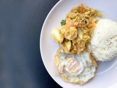 Stir fry karides ve köri güç Tay tarzında siyah kumaş doku arka plan üzerinde beyaz tabak pirinç kızarmış yumurta ile kalamar. Tay tarzında gıda.