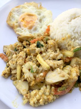 Deniz ürünleri, karides ve sarı toz köri pirinç ve kızarmış yumurta beyaz arka plan üzerinde beyaz tabakta kalamar tavada kızartılmış. Tay tarzında gıda.