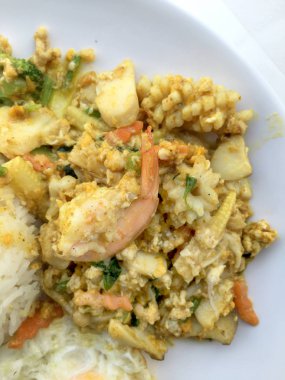 Deniz ürünleri, karides ve sarı toz köri pirinç ve kızarmış yumurta beyaz arka plan üzerinde beyaz tabakta kalamar tavada kızartılmış. Tay tarzında gıda.