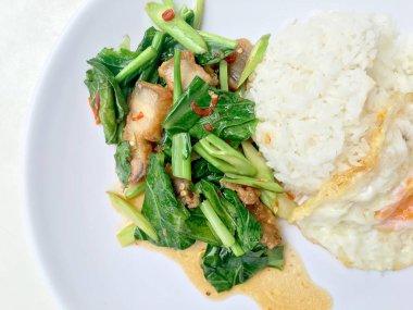 Fry stir Kai arazi ve gevrek domuz eti, beyaz arka plan üzerinde beyaz tabak kızarmış pilav pilav ile karıştırın. Tay tarzında gıda.