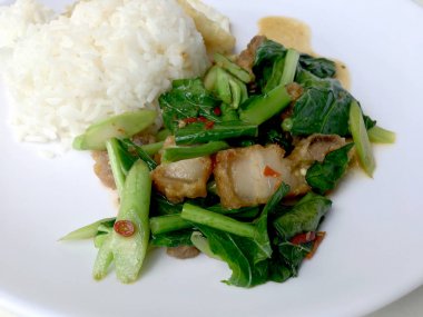 Fry stir Kai arazi ve gevrek domuz eti, beyaz arka plan üzerinde beyaz tabak kızarmış pilav pilav ile karıştırın. Tay tarzında gıda.