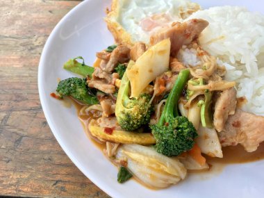 Asya tarzı tavada et dilimleri pilav ve kızarmış yumurta beyaz tabak ahşap masa üzerinde yerleştirilen Tay tarzında taze sebze ile.