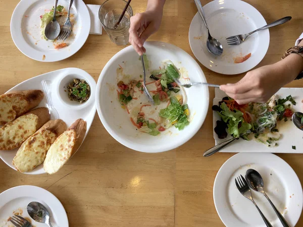 Enjoy eating. Top view of friends, family, group of people have eating healthy food together after vegetarian cooking classes while sitting at the wooden table. Group Of People Dining Concept