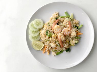 Limon ve beyaz arka plan üzerinde beyaz tabak içinde salatalık Fried rice karides otlar ve sebze ile servis. Dokuz Asya gıda yemekler bir dizi parçası. Tayland gıda.