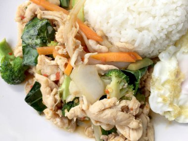 karışık sebze ve pirinç eski ahşap masa üzerinde beyaz tabak içinde Tay tarzında kızarmış yumurta ile tavada kızartılmış tavuk. Asya Tayland gıda.