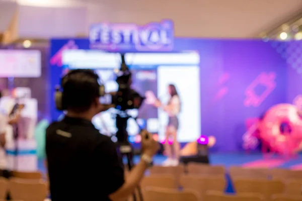 blurred image of young cameraman using a professional camcorder in door at event filming music show or mini concert for shooting some video movie and live broadcasting for online TV commercial