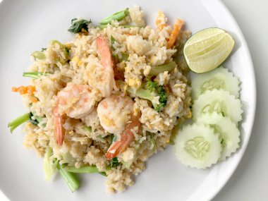 Limon ve beyaz arka plan üzerinde beyaz tabak içinde salatalık Fried rice karides otlar ve sebze ile servis. Dokuz Asya gıda yemekler bir dizi parçası. Tayland gıda.