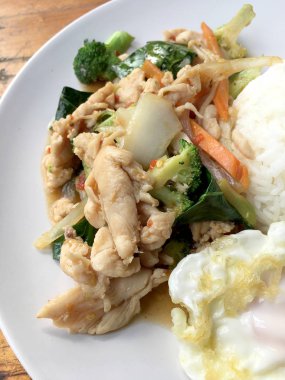 karışık sebze ve pirinç eski ahşap masa üzerinde beyaz tabak içinde Tay tarzında kızarmış yumurta ile tavada kızartılmış tavuk. Asya Tayland gıda.