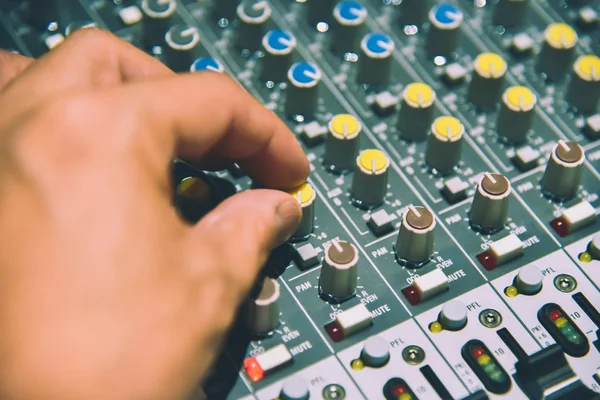 close-up hands of sound engineer adjusting audio mixer controller for live music and studio equipment. This is a quality audio system for professionals. vintage tone & effect light in control room.