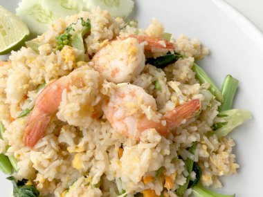 Limon ve beyaz arka plan üzerinde beyaz tabak içinde salatalık Fried rice karides otlar ve sebze ile servis. Dokuz Asya gıda yemekler bir dizi parçası. Tayland gıda.
