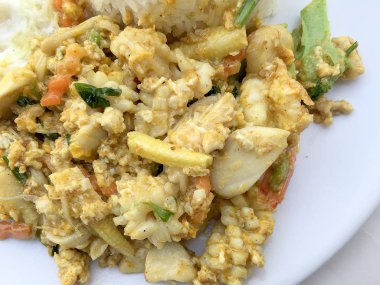Deniz ürünleri, karides ve sarı toz köri pirinç ve kızarmış yumurta beyaz arka plan üzerinde beyaz tabakta kalamar tavada kızartılmış. Tay tarzında gıda.