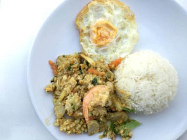 Deniz ürünleri, karides ve sarı toz köri pirinç ve kızarmış yumurta beyaz arka plan üzerinde beyaz tabakta kalamar tavada kızartılmış. Tay tarzında gıda.