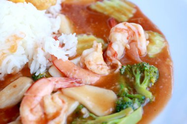 heyecan Kızarmış karides ve brokoli Tay kırmızı köri sosu pilav ile yapıştırın, Kızarmış karides ve beyaz tabak portre ahşap masa üzerinde pişmiş pirinç köri. Tay tarzında gıda.