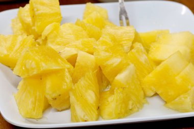 Dilimlenmiş ananas arkaplan dokusunu beyaz tabakta kapat. Kaydır ve bir parça taze meyve.