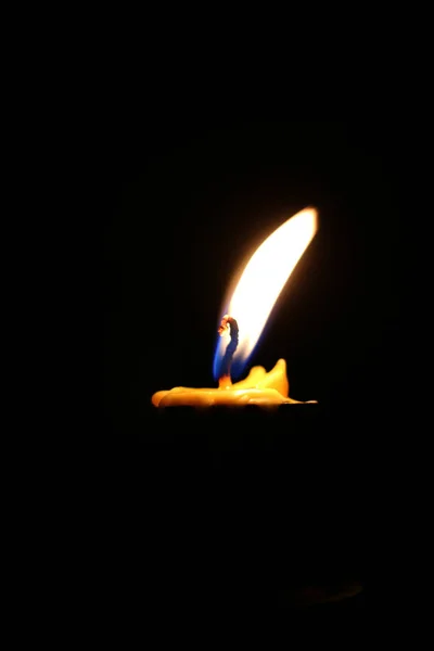 One or Single yellow light candle burning brightly in the black background, candle light isolated black in dark night.