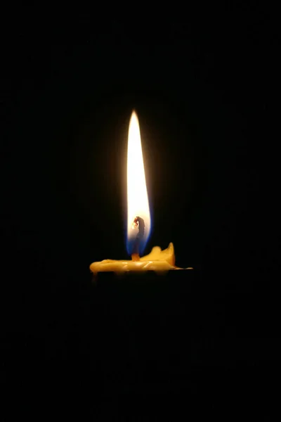 One or Single yellow light candle burning brightly in the black background, candle light isolated black in dark night.