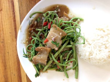 Kızarmış Su Minosa, beyaz tabakta kızarmış domuz eti, pilav ve ahşap masada kızarmış yumurta. Tayland tarzı yemek..