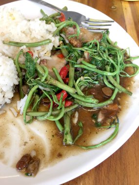 Kızarmış Su Minosa, beyaz tabakta kızarmış domuz eti, pilav ve ahşap masada kızarmış yumurta. Tayland tarzı yemek..