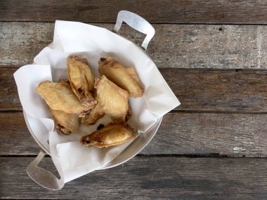 Kovada sarımsak soslu kızarmış tavuk kanadı. Asyalı yemek konsepti için ahşap masada. Tayland tarzı yemek..