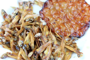 Kızarmış dev yayın balığı ve kızartılmış küçük balıklar (Minnow) geleneksel Tayland tarifleri kırsal ahşap arka planda beyaz tabakta. Tayland 'da popüler, Tayland' ın önemli ihracat ürünü.