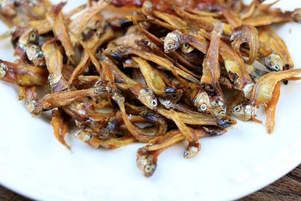 Kızarmış dev yayın balığı ve kızartılmış küçük balıklar (Minnow) geleneksel Tayland tarifleri kırsal ahşap arka planda beyaz tabakta. Tayland 'da popüler, Tayland' ın önemli ihracat ürünü.